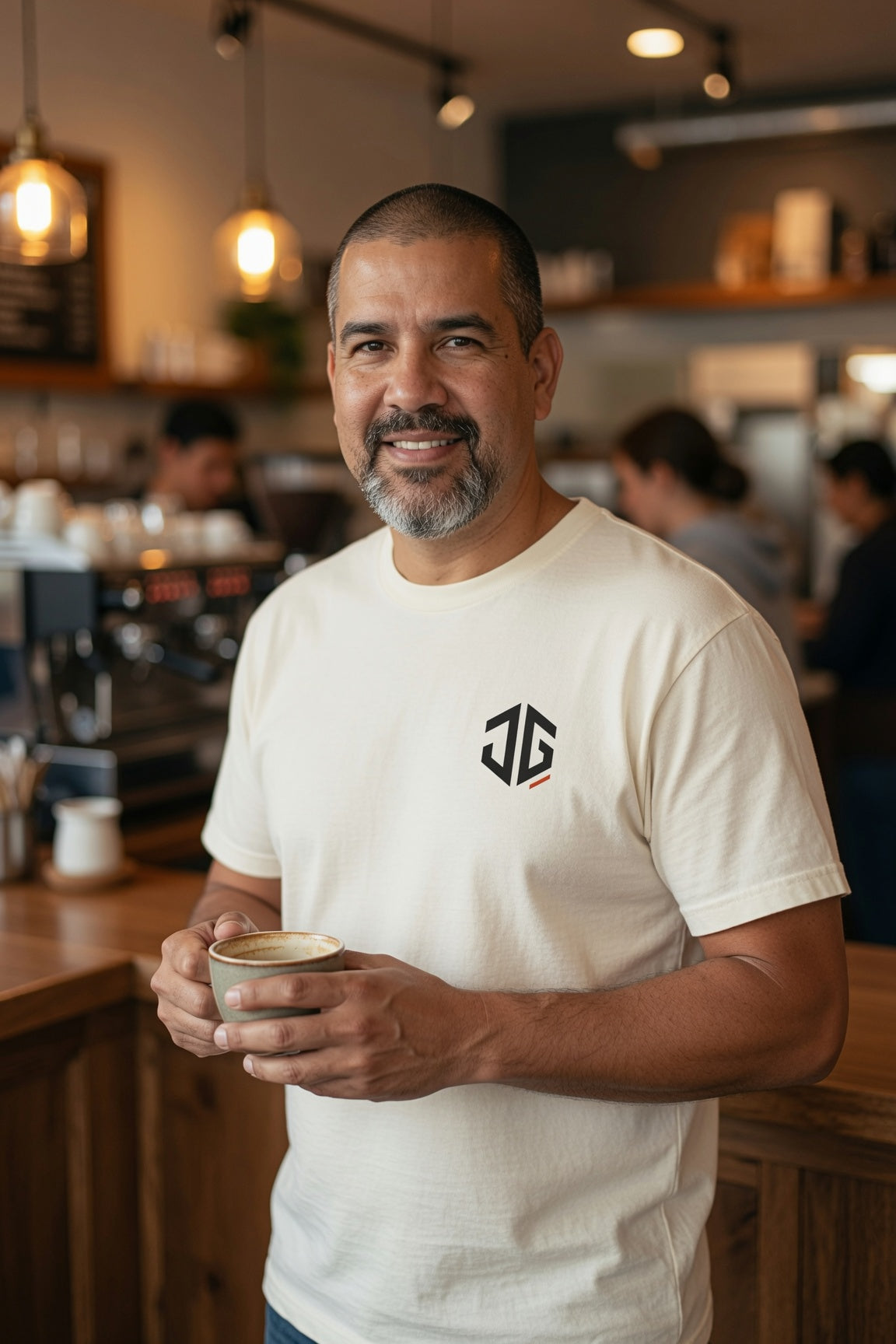 Man wearing an ivory JGTees left-chest garment-dyed tee in a coffee shop