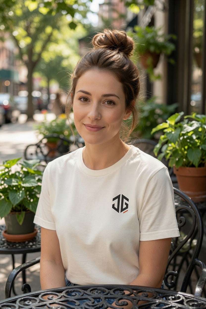 Woman wearing an ivory JGTees left-chest garment-dyed tee at an outdoor café