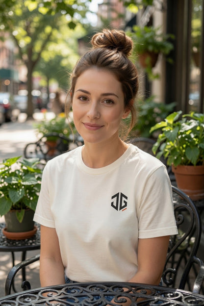 Woman wearing an ivory JGTees left-chest garment-dyed tee at an outdoor café